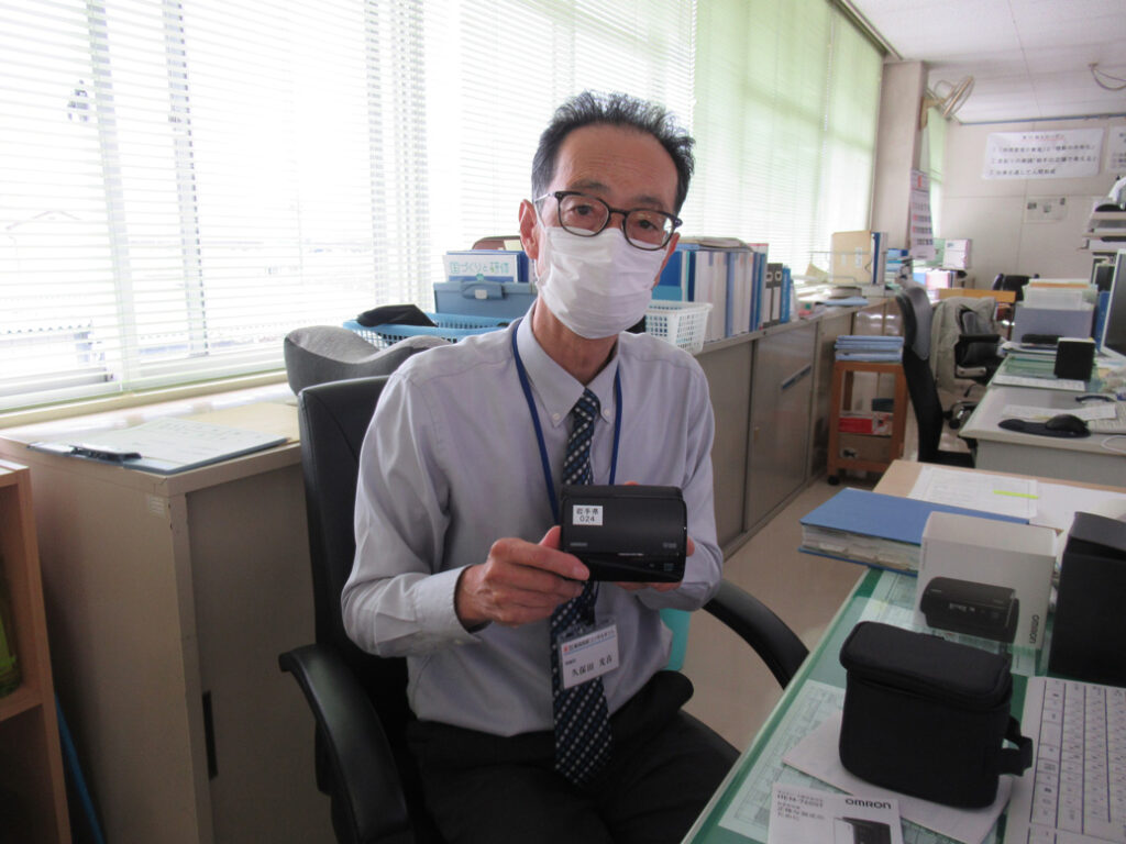 血圧測定器具を持つ社員